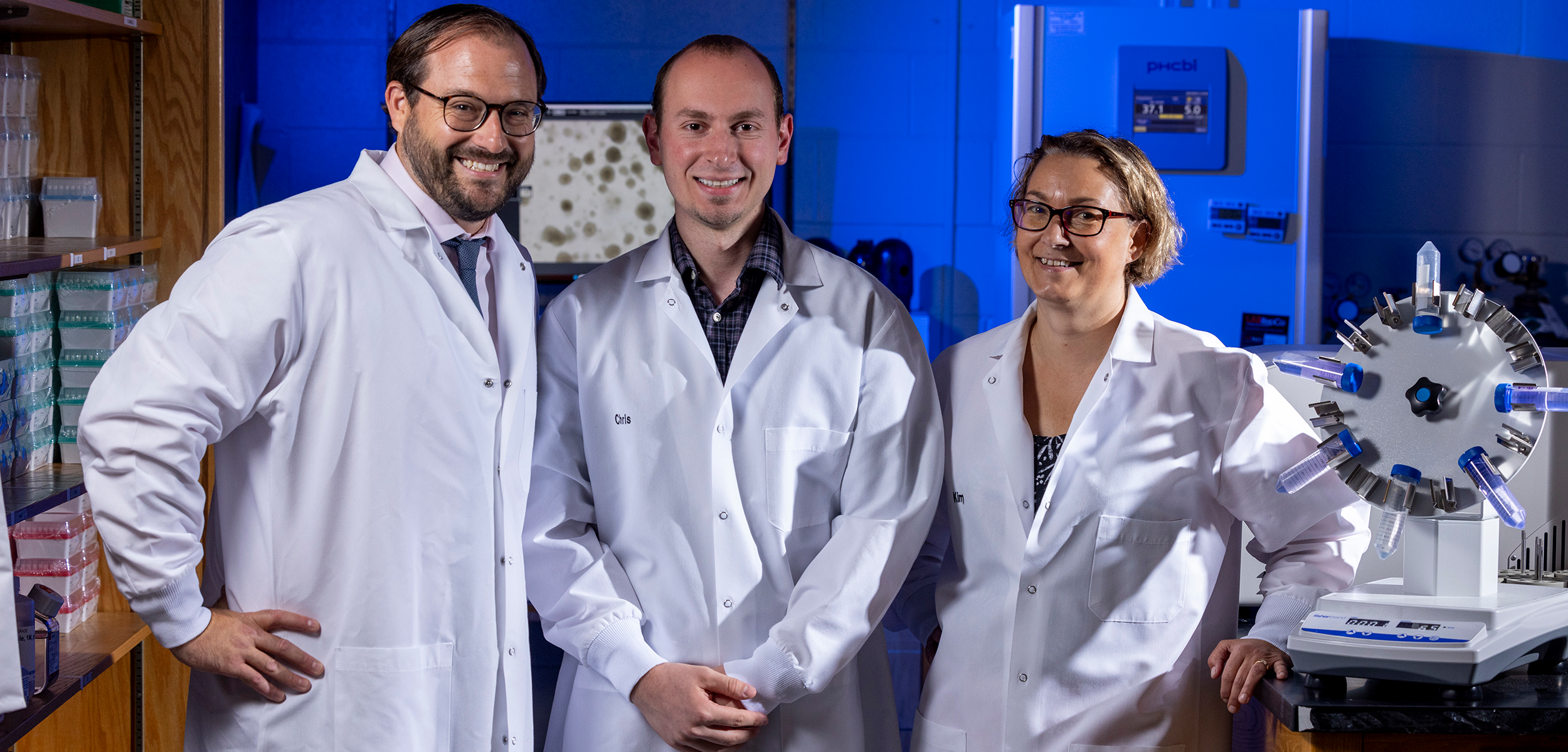 Researchers with white lab coats working with scientific equipment.