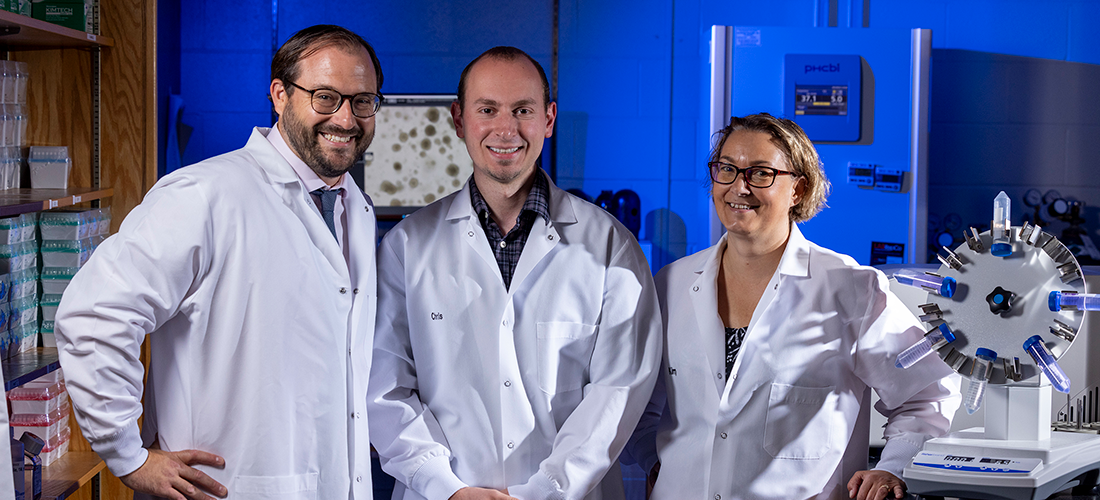 Researchers with white lab coats working with scientific equipment.